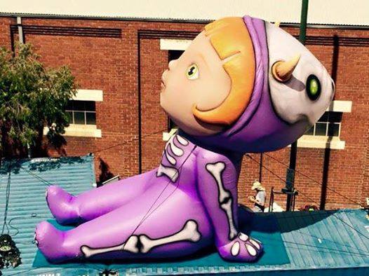 Large inflatable skeleton-themed child character in purple costume on rooftop display.